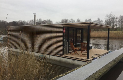 Rustersiel Apartment | Houseboat HT 5 with a fireplace in the lounge, two bedrooms, a kitchen, two bathrooms and a terrace